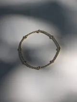 Pulsera elástica compuesta por pequeñas cuentas plateadas de 2 mm y cuentas más grandes de 4 mm espaciadas a lo largo de la circunferencia.