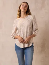 Blusa estampada color beige con cuello redondo calado y mangas 3/4 abullonadas con terminación elastizada.