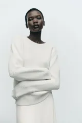 Sweater color blanco de punto perlado, con cuello redondo y mangas largas.