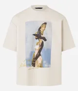 Remera overboxy color crema con estampa frontal de una mujer con un pájaro en la cabeza y lettering bordado.