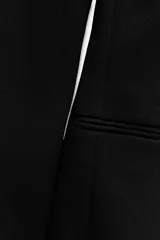 Vestido midi negro de escote pico y manga larga con hombreras. Tiene falsos bolsillos de vivo en el delantero y cierre en la espalda con cremallera oculta.