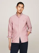 Camisa Tommy Hilfiger de corte slim fit, confeccionada en algodón Oxford con textura dobby. Diseño liso color salmón, con cuello abotonado, mangas largas con puños redondeados y logo bordado en el pecho.