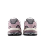 Championes New Balance modelo 2010, color rosa pálido (ice wine) con detalles en gris y entresuela crema. Presentan una silueta deportiva con paneles de malla y gamuza, y la icónica 'N' lateral en gris con borde blanco. La suela incorpora unidades de amortiguación visibles en el talón.