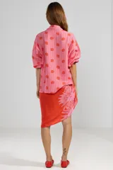 Camisa de manga larga color rosa con rayas verticales rojas y estampado de flores rojas. Tiene cuello camisero, puños elastizados y lazos regulables en los costados del ruedo.