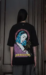 Remera negra de algodón con cuello redondo y calce oversize. Estampa sublimada con ilustración de una mujer con pelo azul y estrellas, espadas y rosas.
