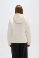 Campera blanca con diseño acolchado, cierre frontal con botones a presión y capucha desmontable.
