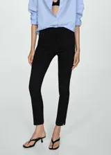 Pantalón negro de corte cigarette, tiro alto y largo tobillero con aberturas laterales.