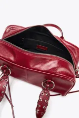 Bolso bowling color rojo con efecto craquelado. Tiene doble asa de hombro con detalles metálicos y asa bandolera extraíble. Incluye bolsillo interior con cremallera y cierre principal con cremallera.