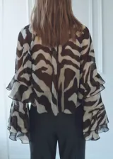 Blusa de manga larga acampanada con estampado animal print bicolor. Tiene cuello pico con lazo, detalle de volantes y diseño recto.