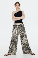 Pantalón de punto de corte holgado con piernas amplias, tiro alto, cintura elástica y cordón para ajustar. Estampado de hojas de palmera en blanco y negro.