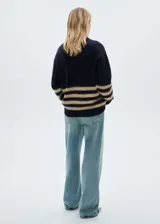 Sweater beige con cuello alto y rayas horizontales negras con hilo dorado.
