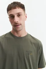 Remera verde militar de manga corta con estampado de soles y texto en la espalda.