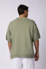 Remera de punto color crema, de manga corta, con cuello redondo acanalado y corte oversize.