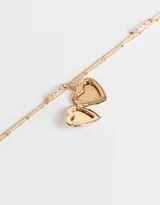 Collar corto dorado de doble cadena, con dije de relicario en forma de corazón con flores rosadas.