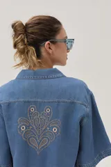 Blusa celeste de denim con cuello camisero, mangas cortas y cierre frontal con botones.