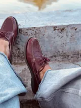Mocasines náuticos color borgoña de cuero con cordones y suela marrón.