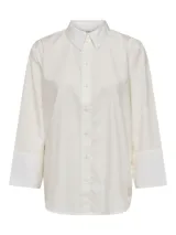 Camisa blanca de corte amplio con cuello clásico, mangas 3/4 tipo box y cierre con botones.