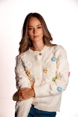 Saco de punto color rojo, con cuello polo y cierre frontal de botones blancos. Presenta flores bordadas en relieve de diferentes colores (azul, amarillo, verde, naranja, rosado) y mangas largas con diseño de burbujas.