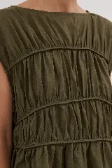 Blusa negra con escote redondo, sin mangas y detalle de frunces horizontales en el frente.