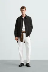 Sobrecamisa negra de tejido con elasticidad, cuello solapa, manga larga con puño abotonado, bolsillos de plastrón en el pecho y cierre frontal con botones a presión.