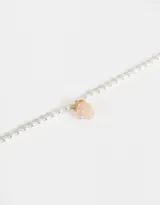 Cadena corta de perlas sintéticas color crema con dije de frutilla rosa y detalles dorados.