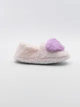 Pantuflas cerradas de tela peluda color rosa pastel, con interior beige y aplique de corazón celeste en el empeine.