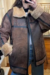 Campera bomber de cuero marrón con cuello y puños de piel sintética color beige.