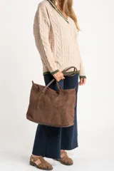 Sweater de lana y nylon color beige jaspeado, con diseño de punto trenzado (cable knit) en todo el cuerpo y mangas. Presenta cuello en V con ribete de dos franjas verdes y puños y bajo con ribete verde liso.