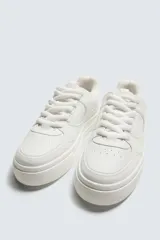 Zapatillas deportivas de estilo retro, color beige y marrón, con cordones y suela gruesa.