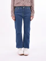 Jean de mezclilla azul de tiro alto, corte acampanado (bootcut) y largo con ruedo deshilachado.