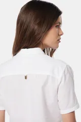 Camisa de lino color beige, de manga corta, con medio botón, dos bolsillos en el pecho y botones metálicos personalizados.