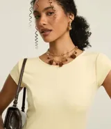 Vestido negro de punto Roma, corto, con escote redondo y mangas cortas. Presenta recortes en el talle que definen la silueta ajustada en el torso y falda acampanada.