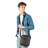 Bandolera negra de cuero con correa ancha de tela con el logo de la marca.