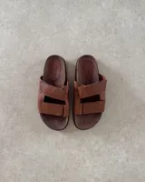 Sandalias bajas de cuero color marrón con doble tira ancha en el empeine.