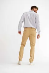 Pantalón de vestir color beige, de corte recto, con bolsillos laterales y traseros. Se ajusta a la cintura con cinturón de cuero marrón.