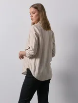 Blusa beige con rayas verticales blancas, escote en V y mangas 3/4 regulables con presilla y botón.
