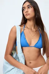 Top de bikini blanco con tirantes finos ajustables al cuello y a la espalda. Presenta volados en el escote y está confeccionado en tejido suave con acabado elástico.