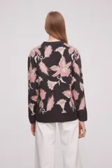 Sweater de acrílico con diseño estampado en tonos rosas y negro, de manga larga y cuello redondo.