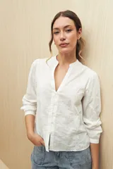 Camisa blanca con bordado floral, cuello mao, escote en V y abotonadura frontal.