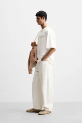 Camiseta blanca de corte holgado, cuello redondo y manga corta. Presenta un pequeño estampado de una estrella azul y un texto en negro en el frente.