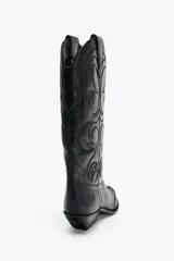 Bota de cuero negra estilo cowboy con bordados marrones, caña ancha, doble tirador y tacón medio.