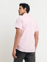 Camisa azul de manga corta, con cuello abotonado y bolsillo en el pecho.