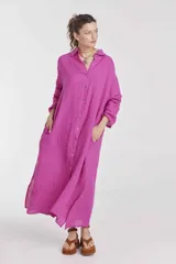 Vestido camisero largo color fucsia, de lino, con cuello camisero, mangas largas, cierre frontal con botones, bolsillos laterales y aberturas laterales en el ruedo.