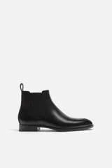 Bota Chelsea de cuero negro, con elástico lateral y tirador trasero.