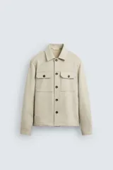 Sobrecamisa color beige de tejido efecto ante, corte regular fit, con cuello solapa, manga larga con puños abotonados, bolsillos de parche con solapa en el pecho y bolsillos de ojal en la cadera.