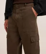 Pantalón baggy color marrón confeccionado en sarga de algodón, con cintura con trabillas, cierre tradicional y bolsillos cargo laterales.