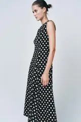 Vestido midi negro con estampado de lunares blancos, cuello redondo y sin mangas.