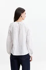 Blusa blanca de manga larga con detalle de tablas en el frente y puños.