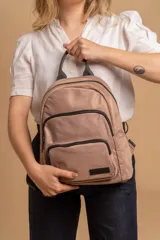 Mochila funcional color beige con detalles en negro, que incluye dos compartimentos con cierre y un bolsillo frontal para fácil acceso.