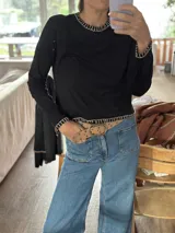 Remera negra de algodón con cuello redondo y bordados blancos en cuello, puños y ruedo. Corte recto.